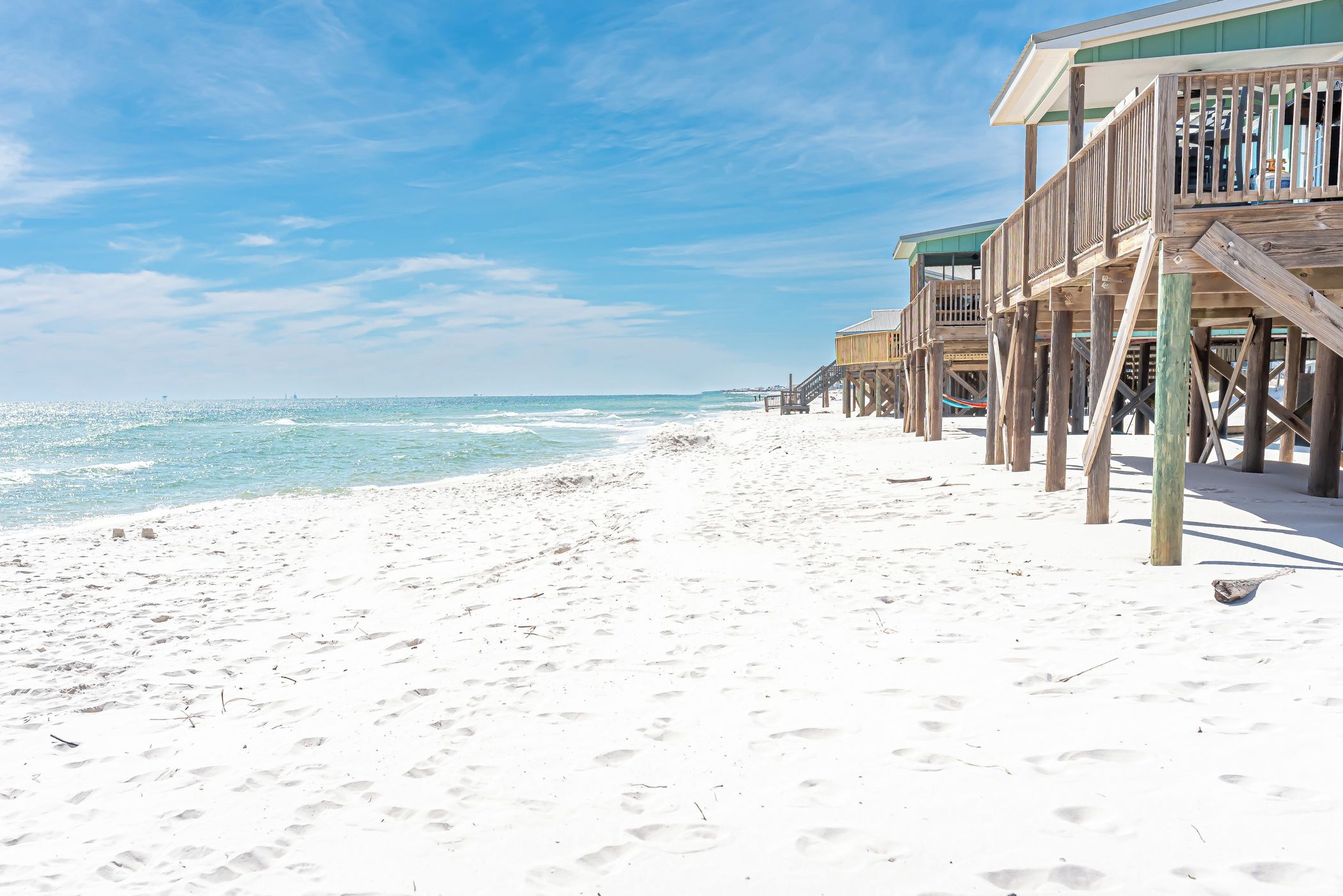 A beach with wooden structures, likely a resort, and a clear sky.