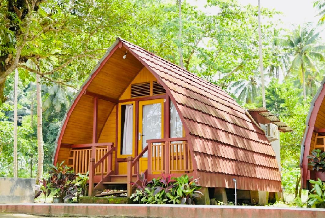 Uma cabana de madeira com telhado inclinado, varanda com grades e uma janela.