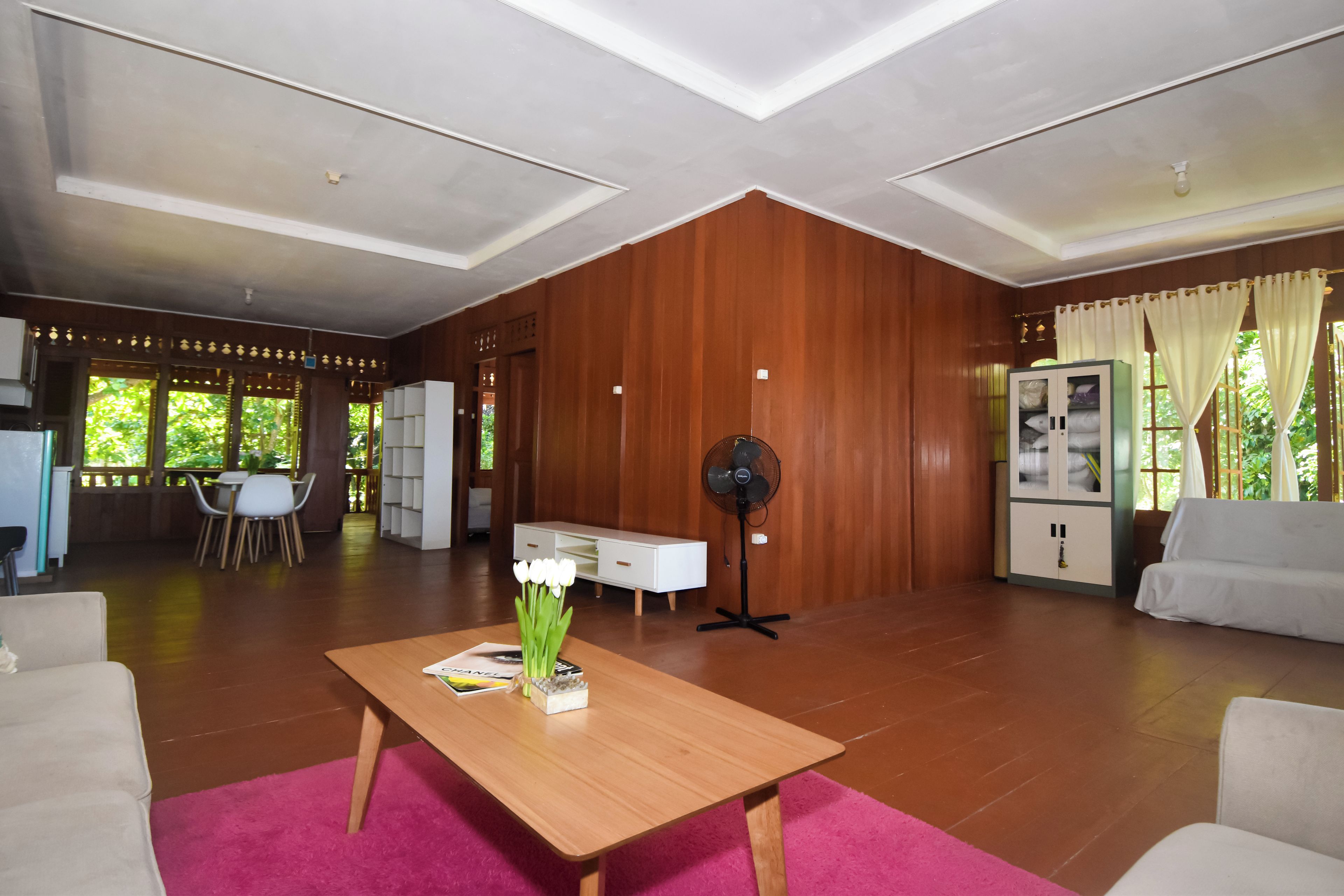 Un espacio habitable amplio con una pared de madera, un comedor con mesa y sillas, y un sofá.