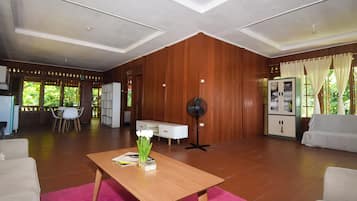 Un espacio habitable amplio con una pared de madera, un comedor con mesa y sillas, y un sofá.