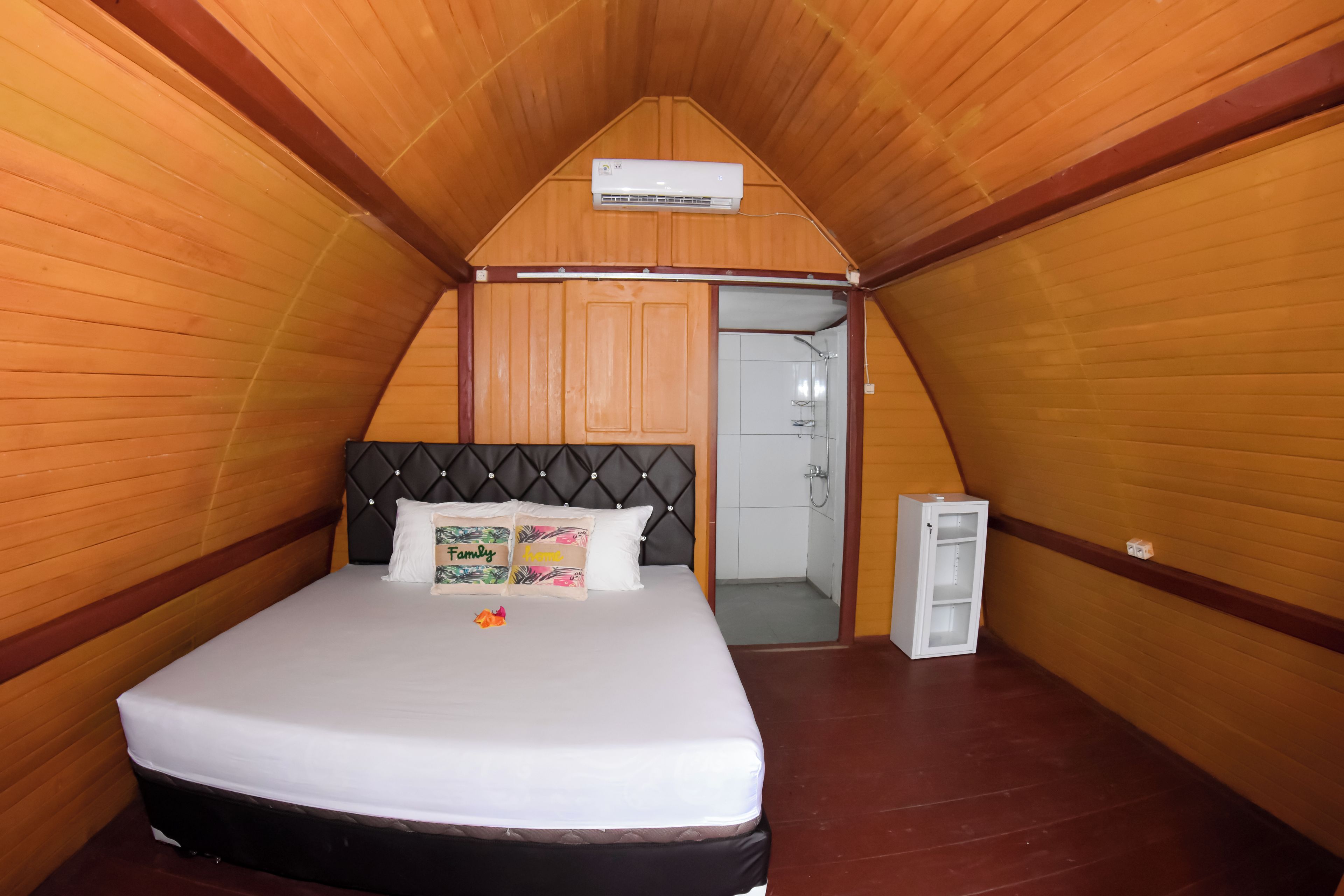 Une pièce comprenant un lit, une petite armoire et une porte donnant sur une salle de bain.