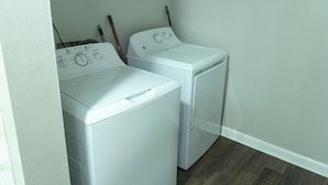 A laundry room with two white front-loading washing machines and a red mop leaning against the wall. - 2-bedroom apartment in pleasant Huntsville with AC and fitness room (Huntsville)