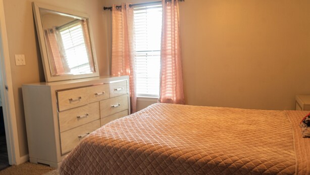 A bedroom with a bed, dresser, and a mirror. - 2-bedroom apartment in pleasant Huntsville with AC and fitness room (Huntsville)
