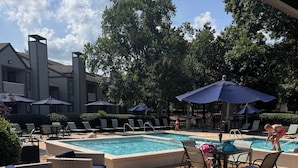 A poolside area with lounge chairs, umbrellas, and a pool. - 2-bedroom apartment in pleasant Huntsville with AC and fitness room (Huntsville)