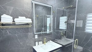 Un bagno moderno con box doccia in vetro, un lavandino bianco con maniglie dorate e un water.