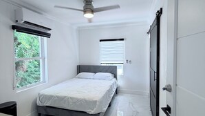 Una camera da letto con un letto, una ventola a soffitto e una finestra.