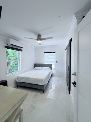 Une chambre à coucher avec un lit, un ventilateur de plafond et une fenêtre.