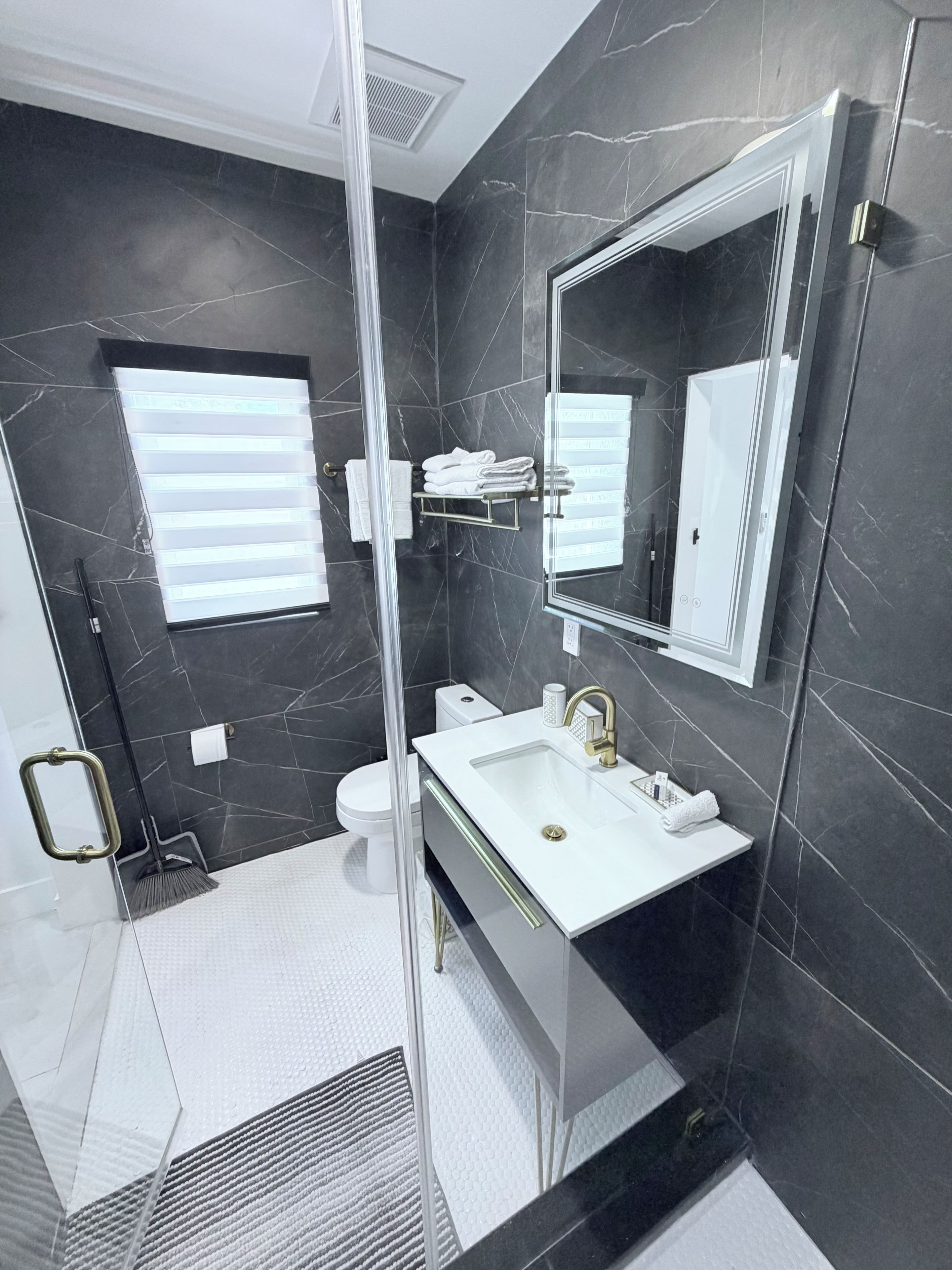 A modern bathroom with a glass shower enclosure, a white sink, and a large mirror.