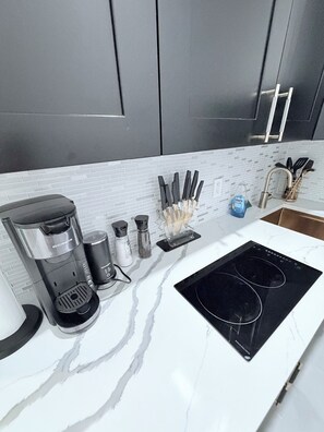Eine Küche mit Kaffeemaschine, Salz- und Pfefferstreuern, einem Messerblock und einer schwarzen Induktionskochplatte.