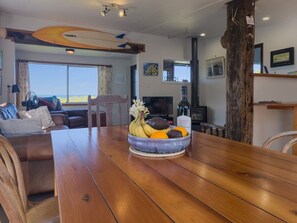 A dining area with a wooden table, a bowl of fruit, and a view of the outdoors.
