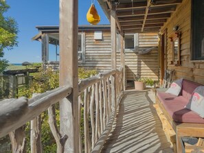 A wooden deck with a cushioned seating area and a hanging yellow object.