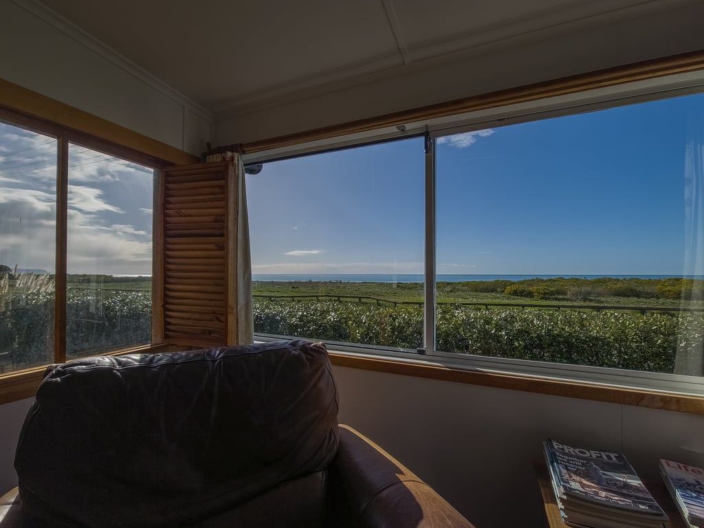 A room with a large window, a leather chair, and a table with magazines.