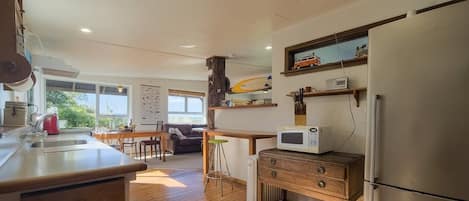 A kitchen with wooden flooring, a refrigerator, a microwave, and a wooden cabinet.