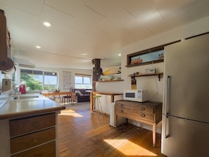 A kitchen with wooden flooring, a refrigerator, a microwave, and a wooden cabinet.