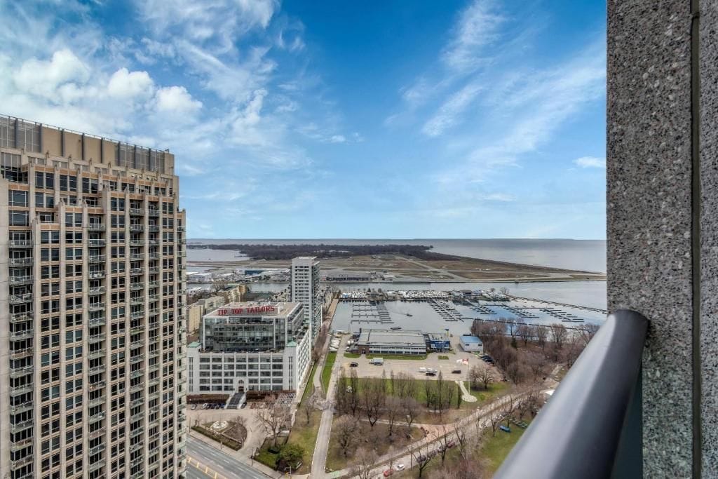 A high-rise building with a view of a waterfront and a parking area.