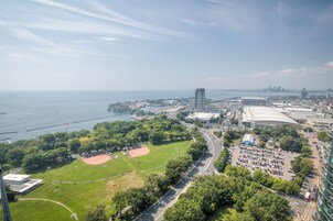 Een hoog hotel met uitzicht op een honkbalveld, een parkeerplaats en een haven met een stadsachtergrond in de verte.