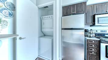 A compact kitchen with a built-in washer and dryer, stainless steel appliances, and dark wooden cabinets.