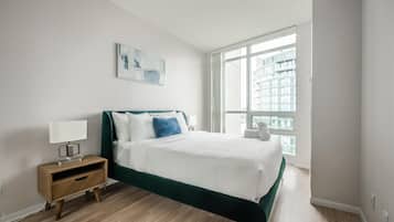 A bedroom with a bed, a nightstand, a window, and a painting on the wall.