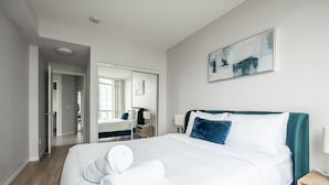 Ein modernes Hotelzimmer mit einem großen Bett, einem Nachttisch, einem Spiegel und einem Bild an der Wand.