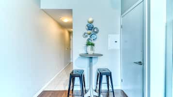 A hallway with a round table, two stools, a wall-mounted plate decoration, and a door.
