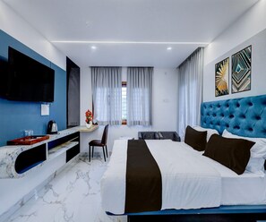 Ein modernes Hotelzimmer mit einem großen Bett, einem Schreibtisch mit Stuhl, einem Flachbildfernseher und Kunstwerken an den Wänden.