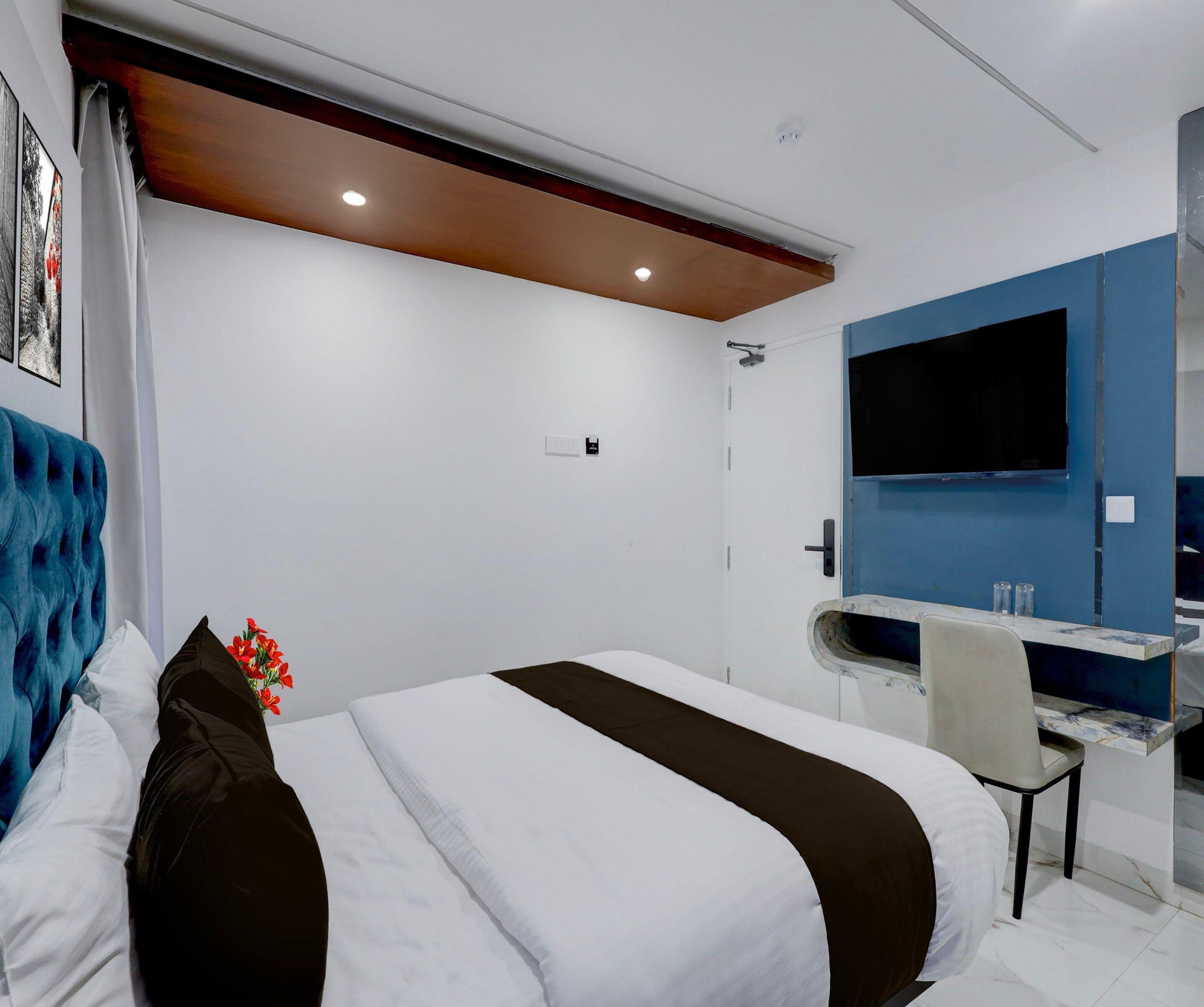 Una habitación de hotel moderna con cama, escritorio, televisión y zona de ducha.