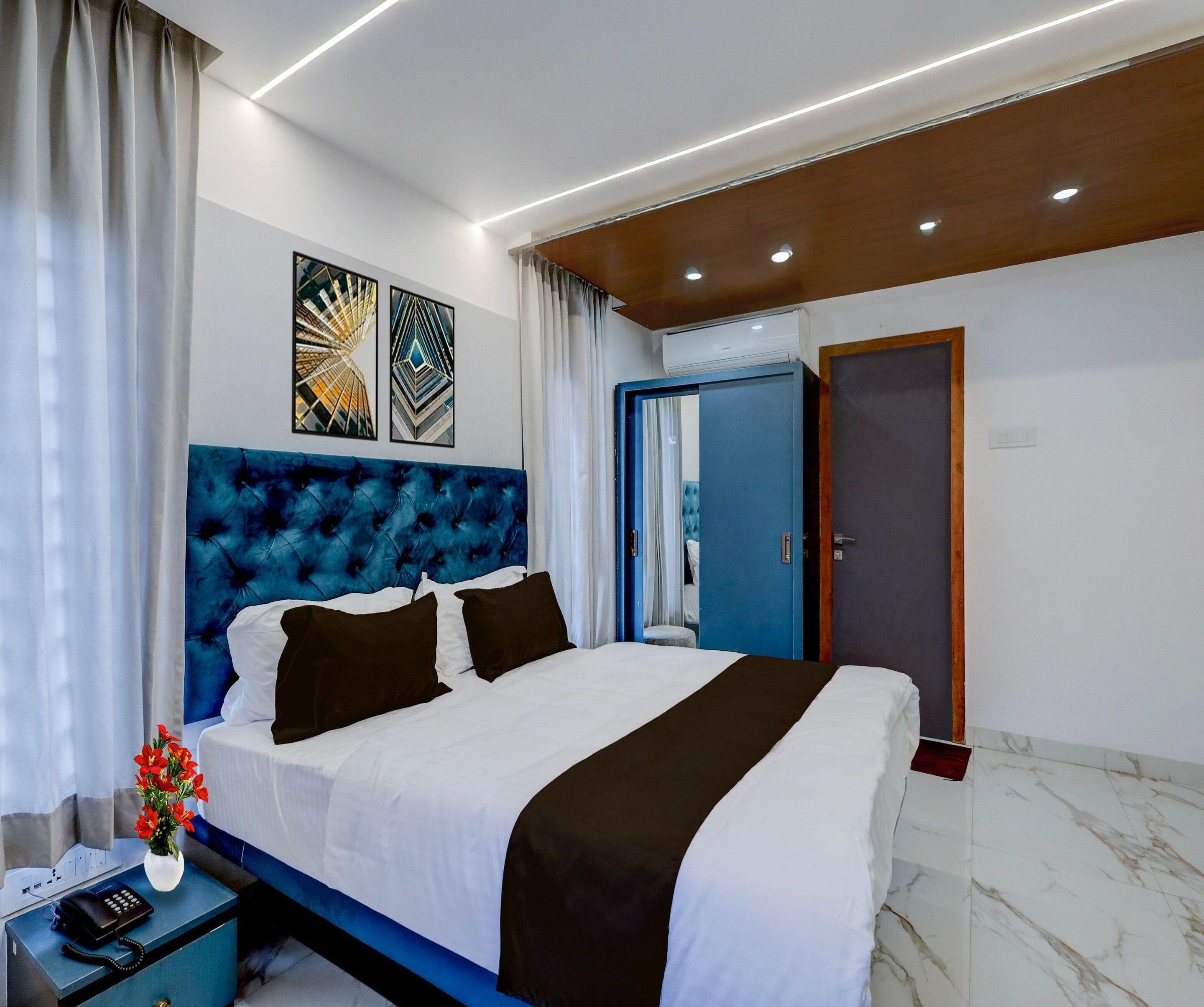 Une chambre d’hôtel moderne avec un grand lit, un téléphone sur la table de chevet et un vase de fleurs.
