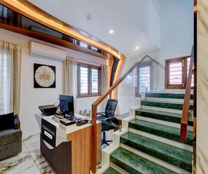 Ein modernes Interieur mit Schreibtisch, Computer und Stuhl, einer Treppe mit grünen Stufen und einem Wandkunstwerk.