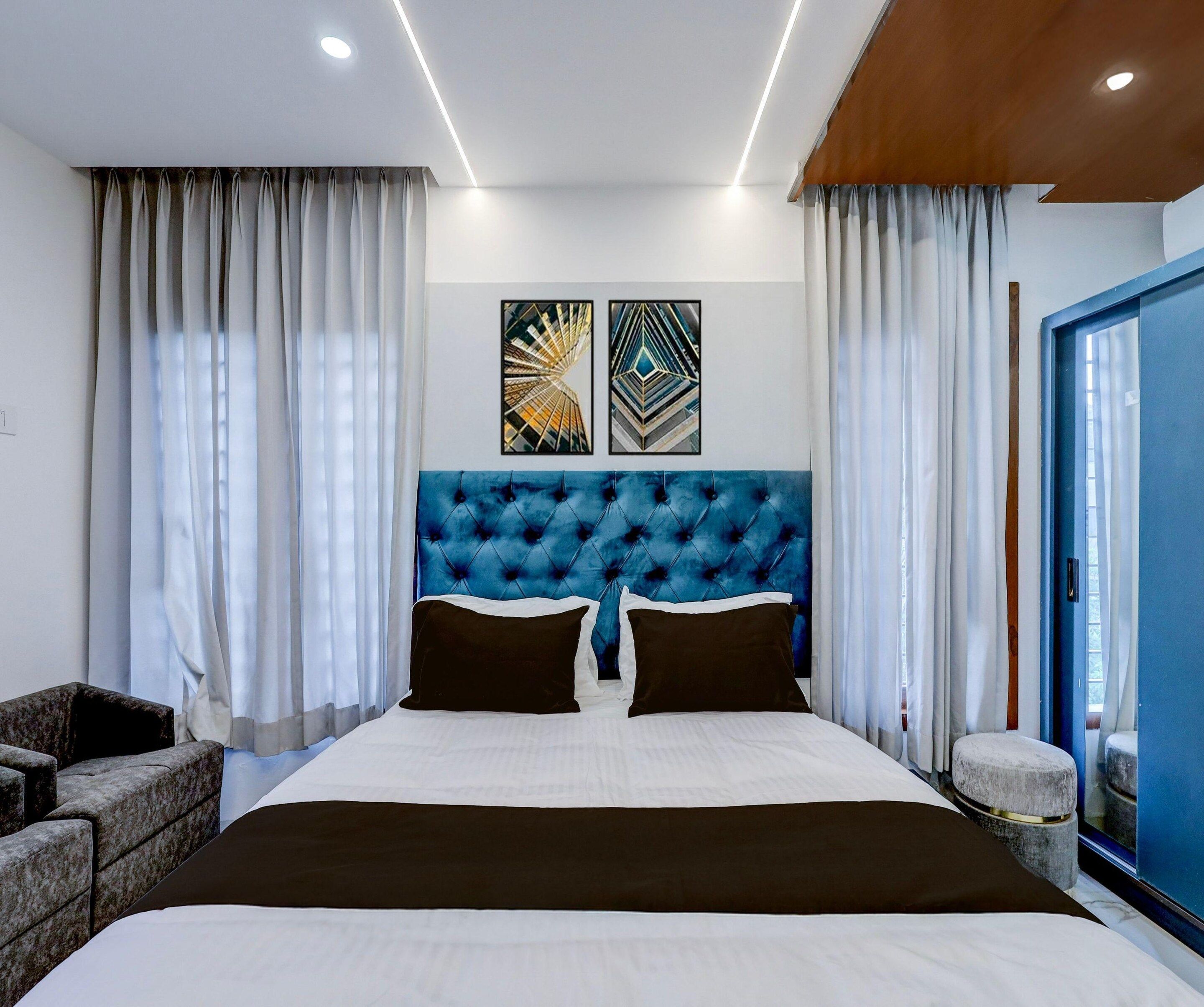 A modern bedroom with a tufted headboard, a bed with white bedding, two black pillows, and a side table.