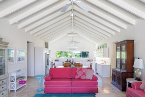 A spacious living area with a high ceiling, a red sofa, and a kitchen in the background. - Tropical Retreat 3-bedroom house in Long Bay Hills (Long Bay Hills)