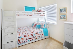 A bunk bed with a lower bunk, a white dresser, a window with blinds, and two framed pictures on the wall. - Tropical Retreat 3-bedroom house in Long Bay Hills (Long Bay Hills)