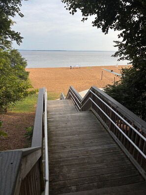 A wooden staircase leading to a beach with a clear view of the sea.