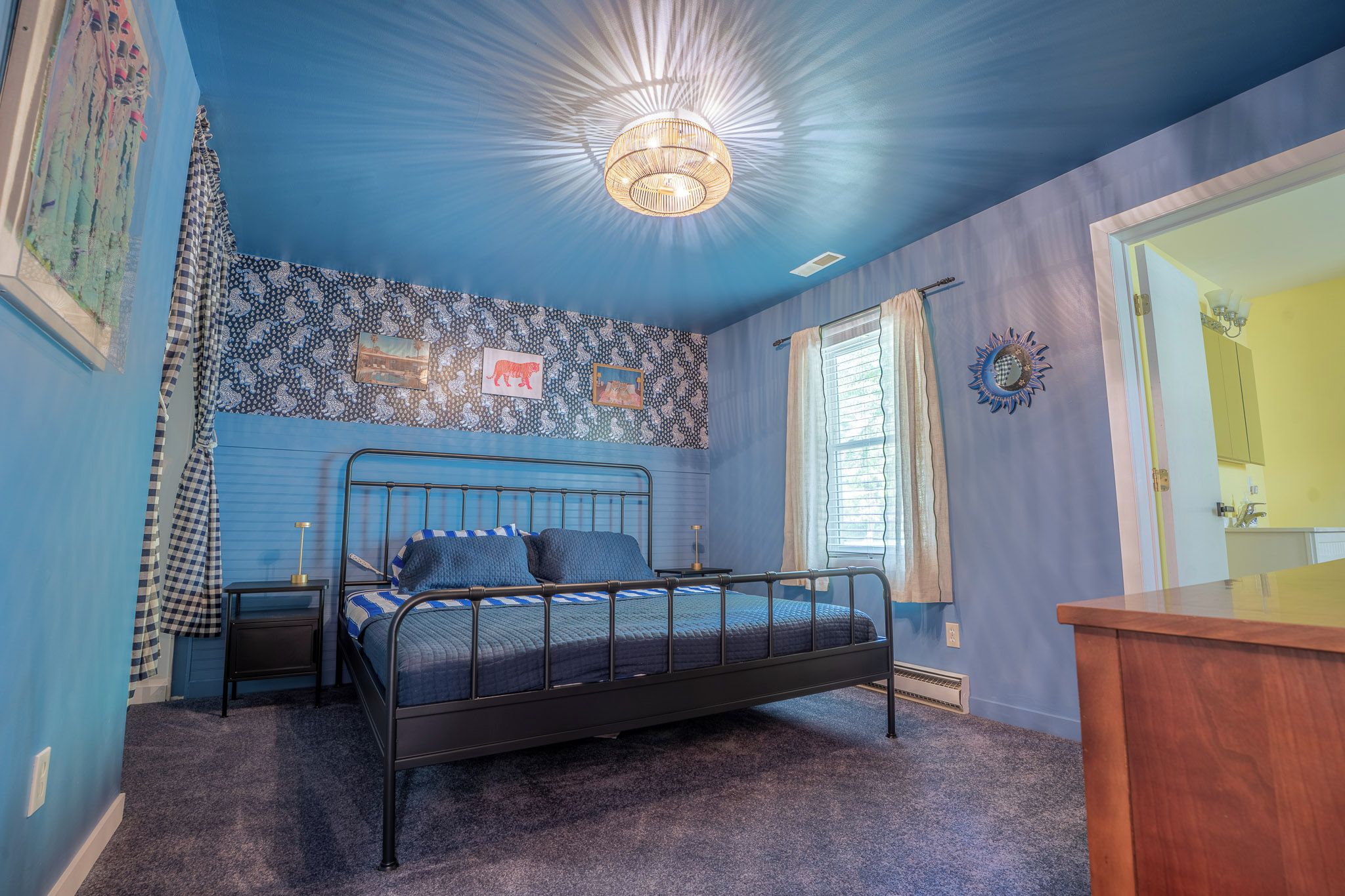 A bedroom with a bed, a nightstand, a dresser, and a window with curtains.