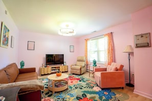 A living room with a television, two sofas, a coffee table, and a patterned rug.