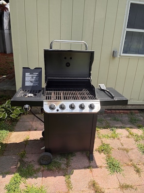 An outdoor grill with four burners, a control panel, and a chimney.