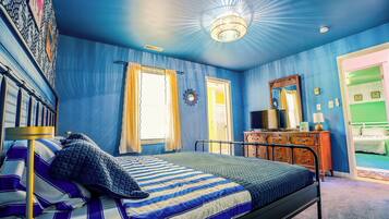 Een slaapkamer met een bed, een dressoir, een spiegel en een deur.