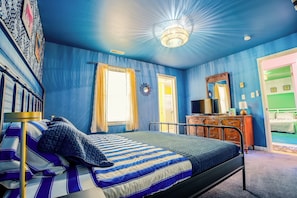 Un dormitorio con una cama, un tocador, un espejo y una puerta.