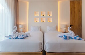 Ein Hotelzimmer mit zwei Betten, jeweils mit weißer Daunendecke, einer Nachttischlampe und einer Wand mit sechs beleuchteten Wandleuchten.