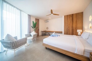 Ein modernes Hotelzimmer mit einem großen Bett, einem Schreibtisch, einem Sessel und einem Deckenventilator.
