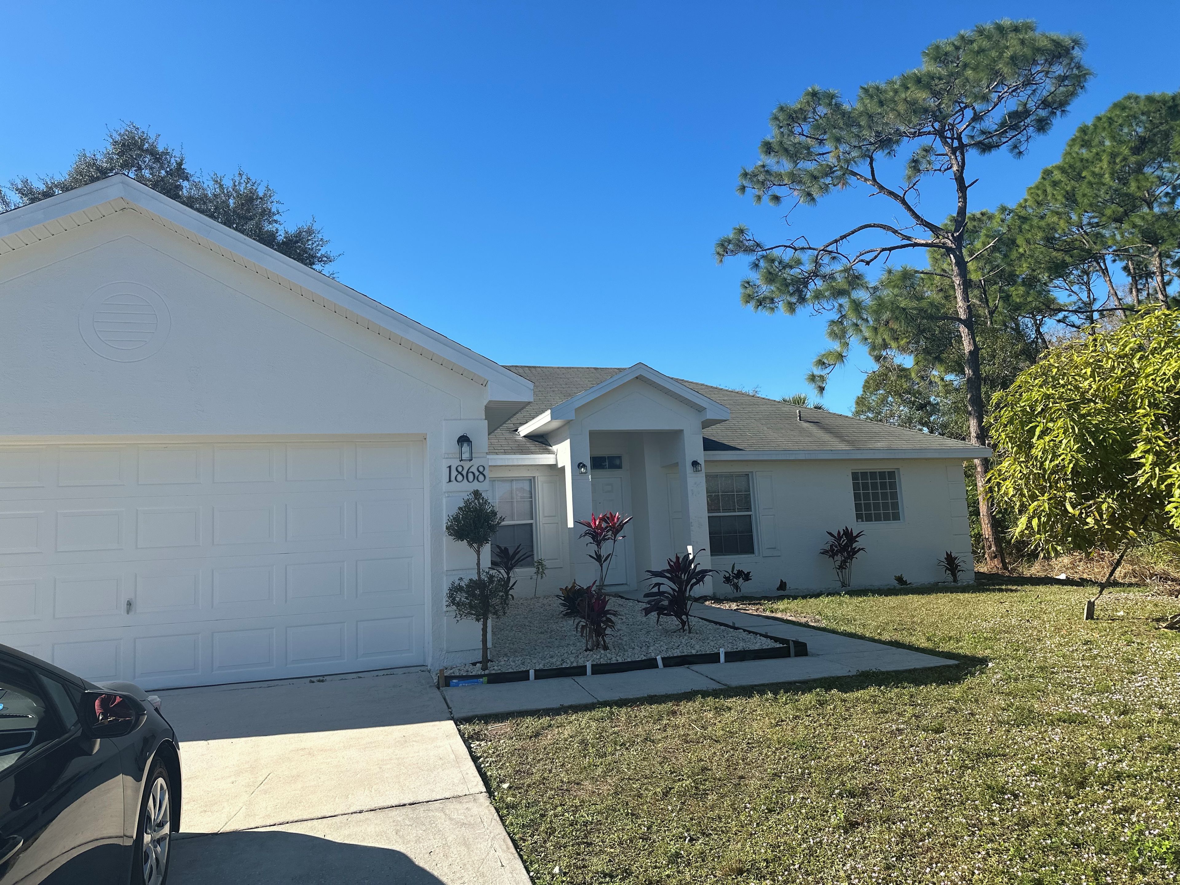 A residential house with a garage, a front porch, and a well-maintained lawn.