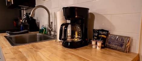 A kitchen with a coffee maker, a sink, and a bag of butter.
