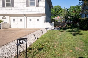 A residential property with a garage, a driveway, and a grassy yard. - Modern Studio - Full Kitchen (Grandview)