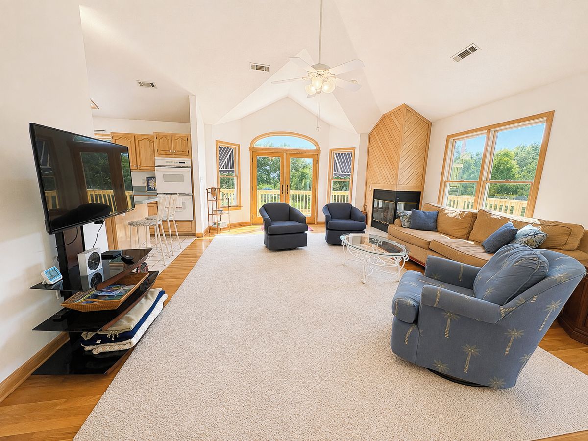 Een ruime woonkamer met een flatscreen televisie, comfortabele zitplaatsen en een groot raam met uitzicht op het omliggende landschap.