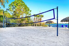 A beach volleyball net with a blue net and white poles, surrounded by sand and palm trees. - 3BR/2BA Bahama Bay Pause in Davenport | Water View, Near Disney (Davenport)