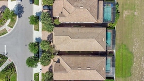 Um bairro residencial com três casas, cada uma com telhado inclinado e piscina.