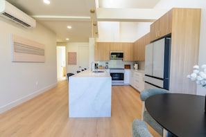 A modern kitchen with wooden cabinets, a central island, and a large refrigerator. - Elevated escape, near UO & Hayward (Eugene)