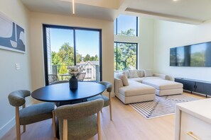 A modern living room with a round table, two armchairs, a sofa, and a TV.