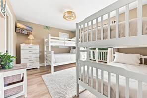 Un dormitorio infantil con literas, un escritorio, una lámpara y un televisor.
