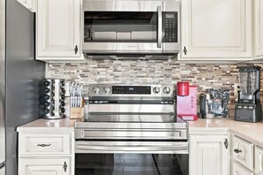 A kitchen with stainless steel appliances, including a microwave, oven, and coffee maker. - Palm Cove | Luxury Channel Home + Coastal Escape (North Myrtle Beach)