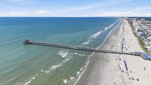 A pier extending into the ocean with a beach and buildings on the shore. - Palm Cove | Luxury Channel Home + Coastal Escape (North Myrtle Beach)